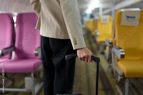 Asian businesswoman dragging a suitcase Walking the airplane aisle to find her seat on a domestic business trip. Online work. Business travel concept.