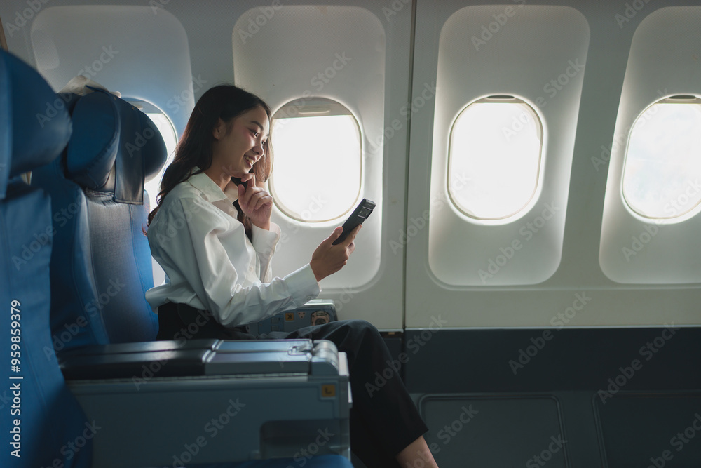 Successful Asian businesswoman Business woman working in airplane on laptop computer and looking out the window while talking on the phone Happy online video calling communication concept.