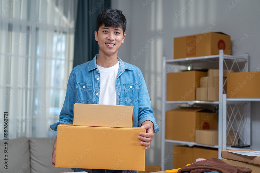 Young Asian man, distributor, online shop owner, small business owner, standing in warehouse and preparing to ship goods, with parcel boxes. Young Asian man, distributor, online shop owner, small business owner, standing in warehouse and preparing to ship goods, with parcel boxes.