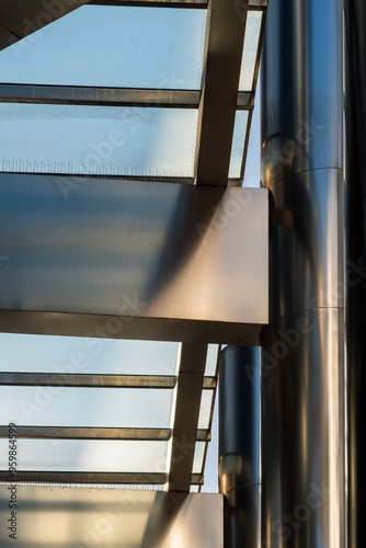 A close-up perspective showing a modern architectural ceiling with metallic beams and large glass panels, highlighting the structure’s elegant and futuristic design. photo