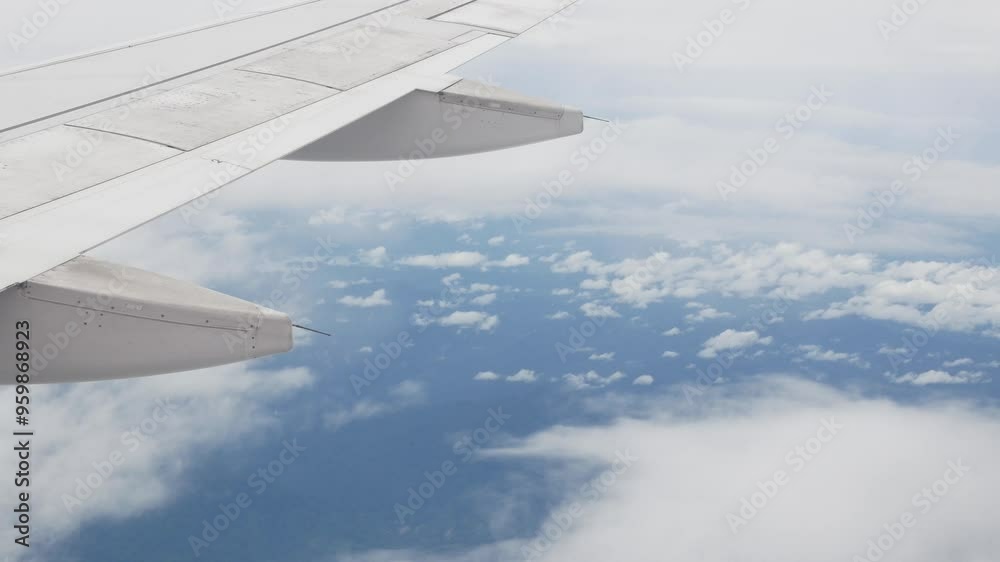 view through aircraft window with plane's wing over blue sky with white fluffy clouds from airplane flight fly over the clouds in a sunny day with cloud moving,summer travel vacation background view through aircraft window with plane's wing over blue sky with white fluffy clouds from airplane flight fly over the clouds in a sunny day with cloud moving,summer travel vacation background