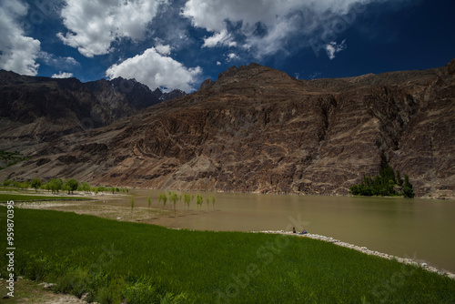 View of the serene Gilgit River flowing through a picturesque valley surrounded by majestic mountains and lush greenery, Ghizer District, Pakistan. photo