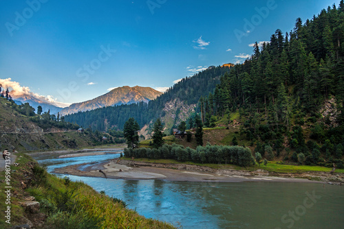 View of beautiful landscape with a serene river, majestic mountains, and lush forest, Kashmir, Pakistan. photo