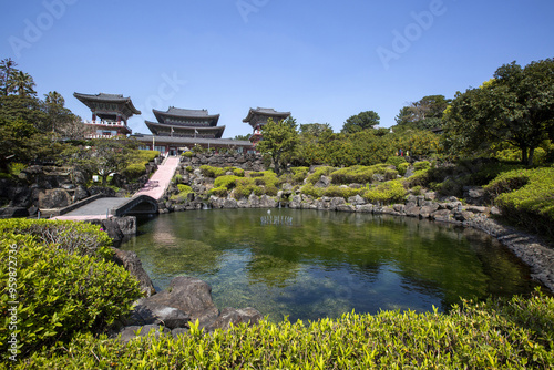 Seogwipo-si, Jeju-do, South Korea - March 23, 2021: Spring view of small pond with garden in spring against Daeungjeon Hall at Yakcheonsa Temple photo