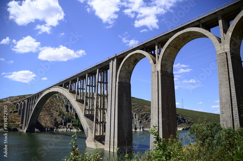 Very high stone bridge with many arches over the river.