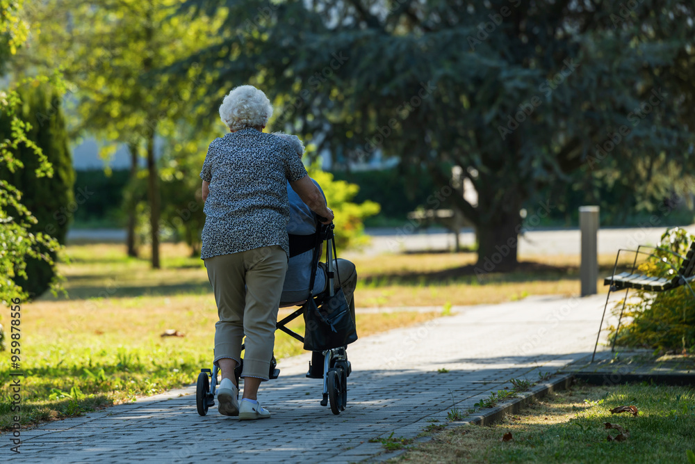 Eine ältere Frau schiebt ihren Mann der auf einem Rollator sitzt