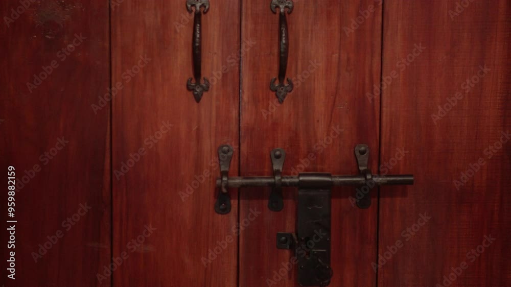 A sturdy wooden door with intricate iron handles and a large latch in a rustic setting A sturdy wooden door with intricate iron handles and a large latch in a rustic setting