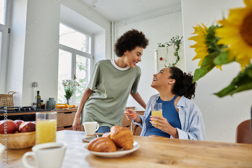 Two women share laughter and drinks while enjoying breakfast together at home. Two women share laughter and drinks while enjoying breakfast together at home.