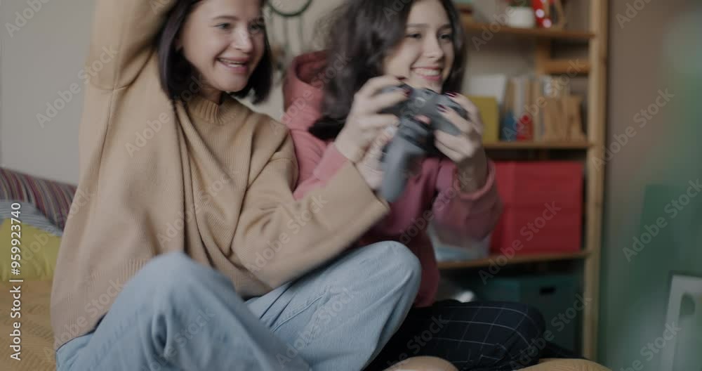 Excited woman and teenage girl playing video game together enjoying competition having fun in bedroom at home. Gaming and family concept. Excited woman and teenage girl playing video game together enjoying competition having fun in bedroom at home. Gaming and family concept.