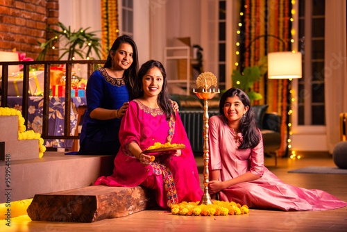 Indian girls creating a beautiful rangoli with flowers, lighting samai diya for Diwali festival photo