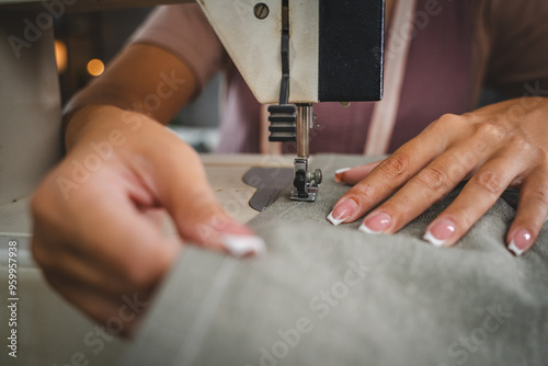 Close up on hands of unknown woman sewing on electric sewing machine