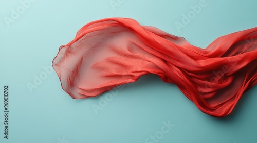 A flowing red piece of fabric captured mid-motion, held against a blue backdrop, highlighting the fluidity and ethereal qualities of the fabric. photo