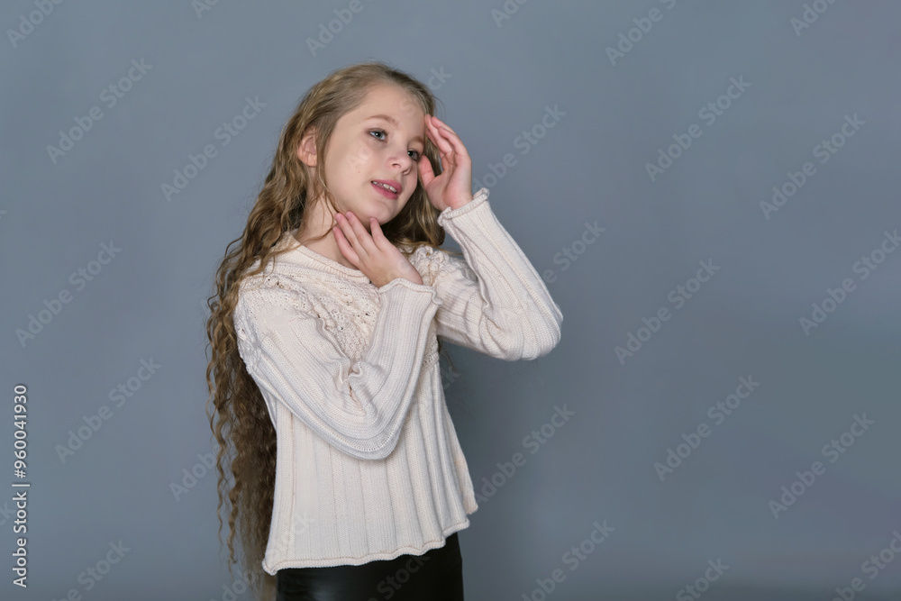 A young girl with long, wavy hair gently touches her face while wearing a cozy sweater, showcasing her natural beauty. This image highlights the importance of children's hair care and promotes A young girl with long, wavy hair gently touches her face while wearing a cozy sweater, showcasing her natural beauty. This image highlights the importance of children's hair care and promotes