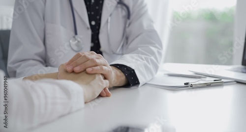 Doctor and a patient. The female physician, wearing a white medical coat over a dark blue dotted blouse, is reassuring a woman during a consultation in the clinic. Medicine concept