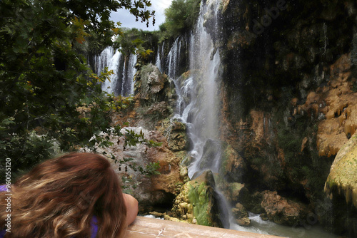 Blonde woman watching waterfall. Nature background. photo