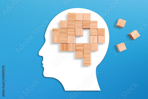 Mental health and problems with memory. Brain shaped puzzle made of wooden cubes on blue background. Missing pieces of the brain puzzle.