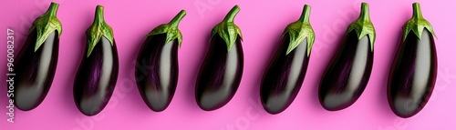 A vibrant display of fresh eggplants arranged neatly on a pink background, showcasing their smooth, glossy texture. photo