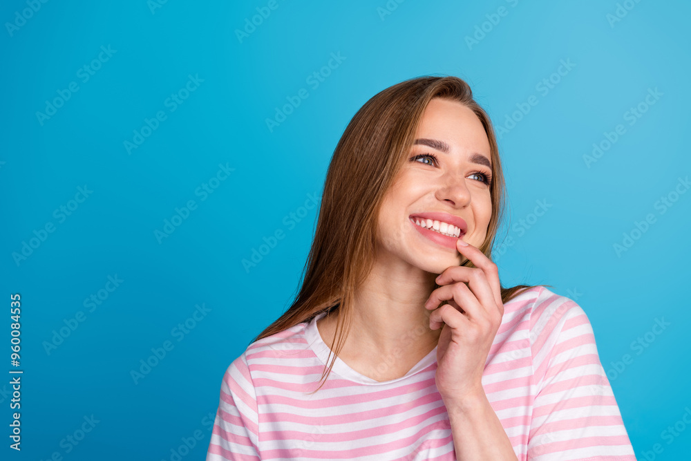 Photo portrait of attractive young woman dreamy look empty space dressed stylish striped pink clothes isolated on blue color background Photo portrait of attractive young woman dreamy look empty space dressed stylish striped pink clothes isolated on blue color background