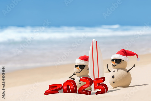 Tableau sur toile Two sandy snowmen on a beautiful beach, wearing sunglasses and with a surfboard
