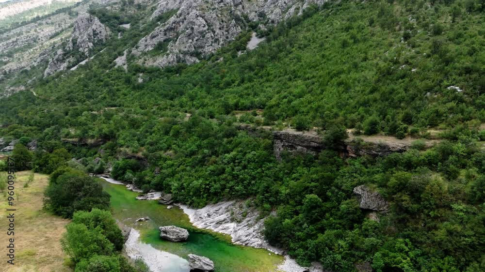 Flying over and crossing the Moraca River Revealing the wide landscape of Montenegro with its river greens, mountains and valley near Podgorica at the Lutovo mountains during august summer aerial Flying over and crossing the Moraca River Revealing the wide landscape of Montenegro with its river greens, mountains and valley near Podgorica at the Lutovo mountains during august summer aerial