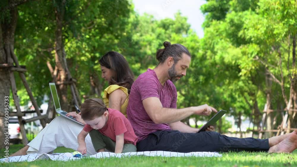 Happy family sitting picnic in a park . mother and father working with laptop and tablet son drawing and painting resting in garden . holiday working activity busy family . Every man for himself Happy family sitting picnic in a park . mother and father working with laptop and tablet son drawing and painting resting in garden . holiday working activity busy family . Every man for himself