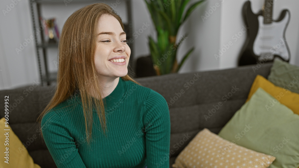 Smiling young caucasian woman with blonde hair dressed in a green sweater inside a cozy living room with a guitar in the background, exuding a relaxed home vibe. Smiling young caucasian woman with blonde hair dressed in a green sweater inside a cozy living room with a guitar in the background, exuding a relaxed home vibe.
