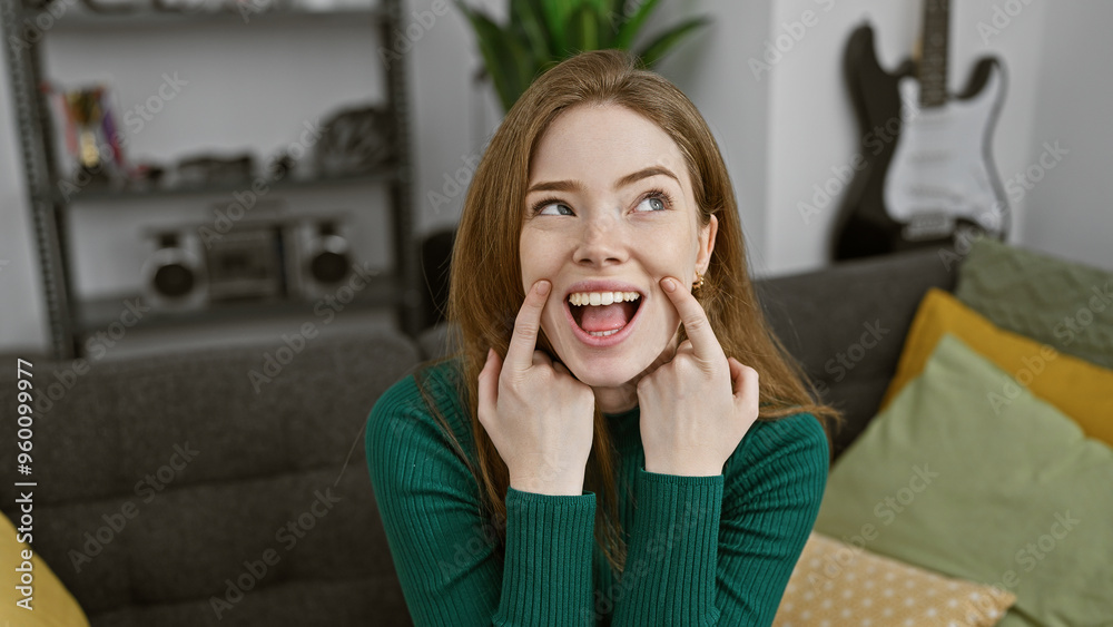 A cheerful young blonde woman in a green sweater posing playfully indoors in a cozy living room A cheerful young blonde woman in a green sweater posing playfully indoors in a cozy living room