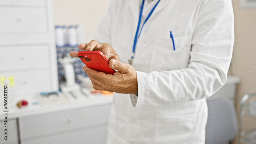 Middle-aged hispanic man in white lab coat using smartphone in hospital setting. Middle-aged hispanic man in white lab coat using smartphone in hospital setting.