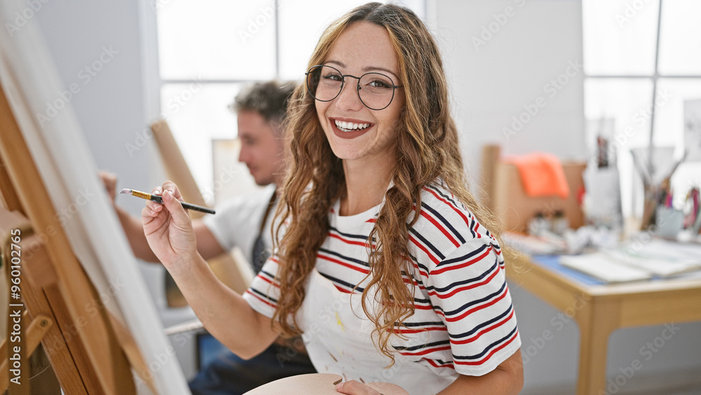 Smiling woman and man artist couple painting together in a bright art studio Smiling woman and man artist couple painting together in a bright art studio