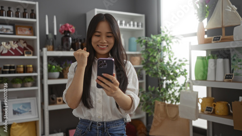 Young woman celebrating while looking at her phone in a beautifully decorated home decor shop filled with various decorative items in china.