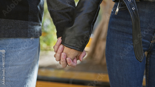 A couple holding hands on a city street, showing love and connection in an urban outdoor setting.