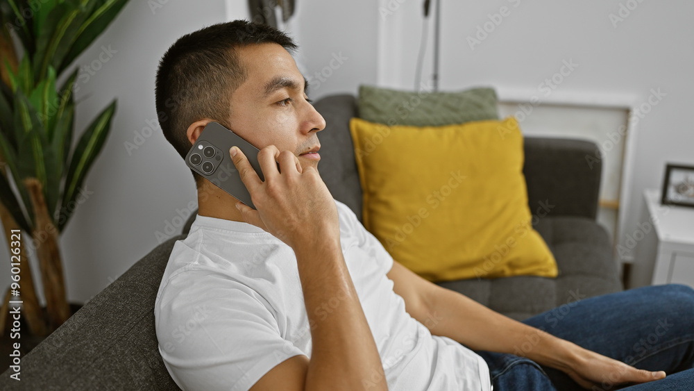 Young hispanic man talking on the phone in a modern living room. Young hispanic man talking on the phone in a modern living room.