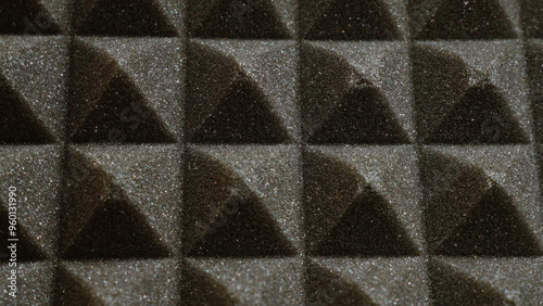 Closeup of black acoustic foam panels with a textured surface arranged in a pattern for soundproofing and noise reduction in a studio or recording environment