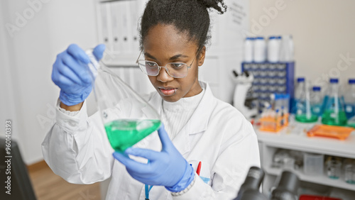 African woman scientist analyzing a green solution in a laboratory.