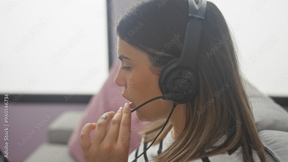 Focused young woman with headset working indoors at customer service job Focused young woman with headset working indoors at customer service job