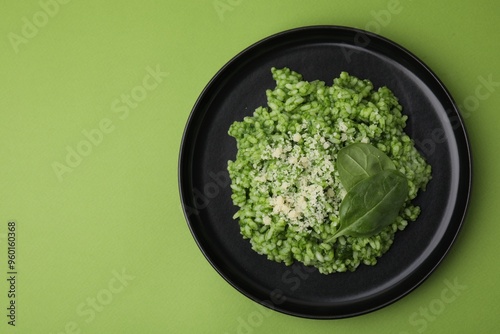 Delicious spinach risotto with parmesan cheese on light green background, top view. Space for text