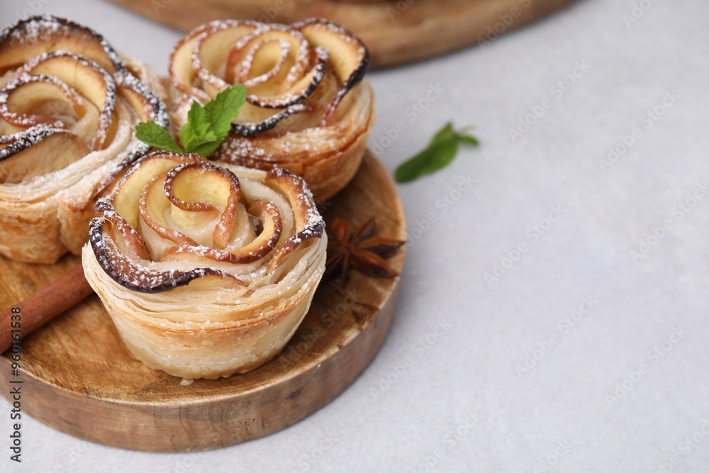 Freshly baked apple roses with mint, cinnamon and anise star on light table, closeup. Space for text Freshly baked apple roses with mint, cinnamon and anise star on light table, closeup. Space for text