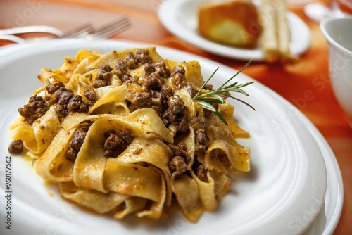 Plate with pappardelle with wild boar ragout sauce on a laid table