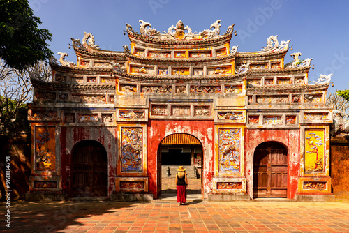 Graceful Passage: Blond european female tourist in front of Cua Tho Chi Gate is exploring the Imperial Citadel in Imperial City Hue, Vietnam