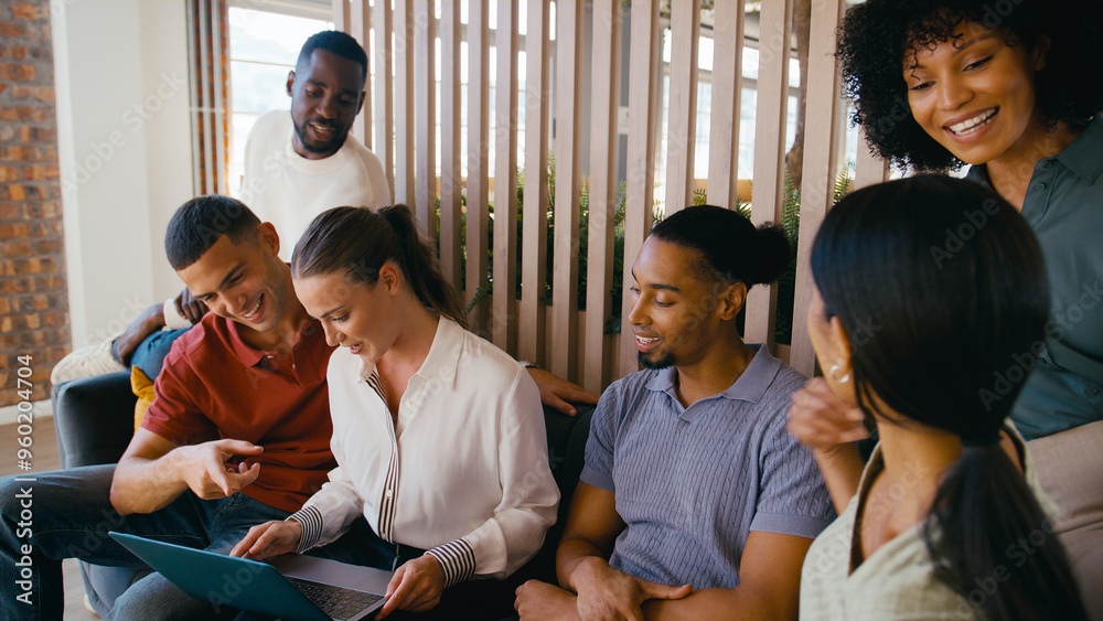 Multi-Cultural Business Team Sitting On Couch In Modern Open Plan Office Working On Laptop Together Multi-Cultural Business Team Sitting On Couch In Modern Open Plan Office Working On Laptop Together
