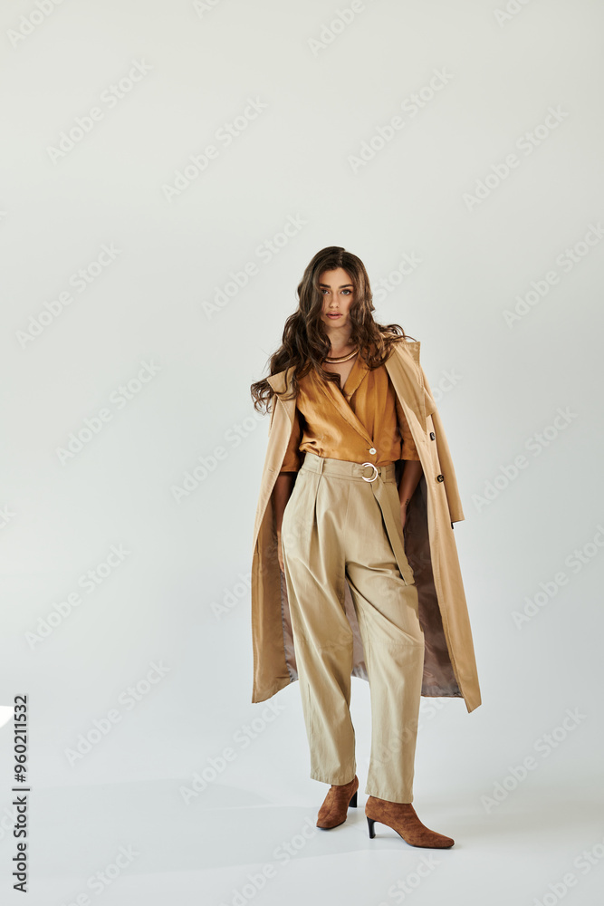 In a serene studio, a beautiful young woman confidently models her chic autumn attire, embodying seasonal elegance.