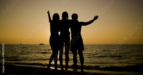 Wallpaper Mural Three friends embracing and waving during a stunning sunset at the beach Torontodigital.ca