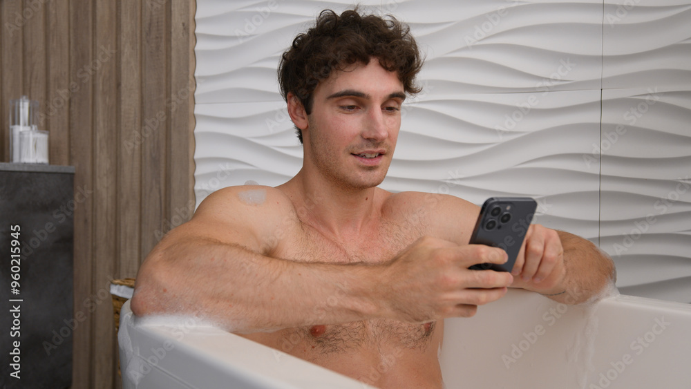 Caucasian happy smiling man in foam bath washing relaxing in foamy bathe using mobile phone scrolling smartphone gadget addict enjoy bathing at home hotel bathtub bliss male guy chatting social media Caucasian happy smiling man in foam bath washing relaxing in foamy bathe using mobile phone scrolling smartphone gadget addict enjoy bathing at home hotel bathtub bliss male guy chatting social media
