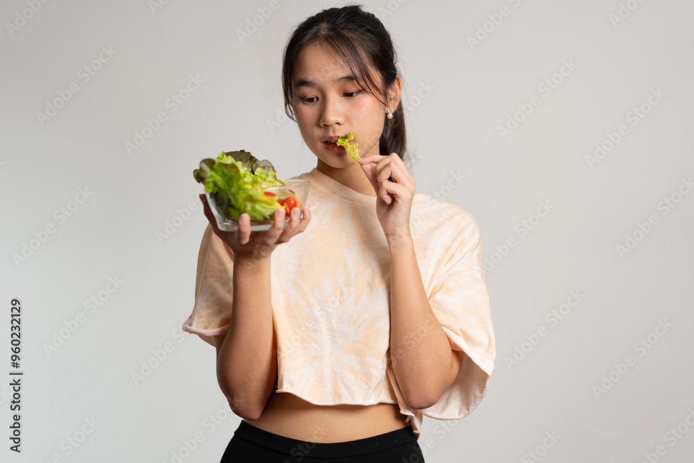 Portrait of a happy playful Asian girl eating fresh salad from a glass bowl after workout at home. Young lady Enjoying Healthy Nutrition And Organic Food, Having Vegetarian Meal Portrait of a happy playful Asian girl eating fresh salad from a glass bowl after workout at home. Young lady Enjoying Healthy Nutrition And Organic Food, Having Vegetarian Meal