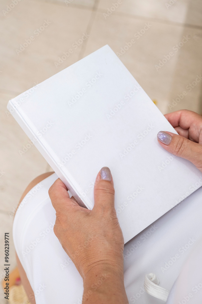 Obraz premium unrecognizable woman holding blank magazine for mockup design, sitting on bench