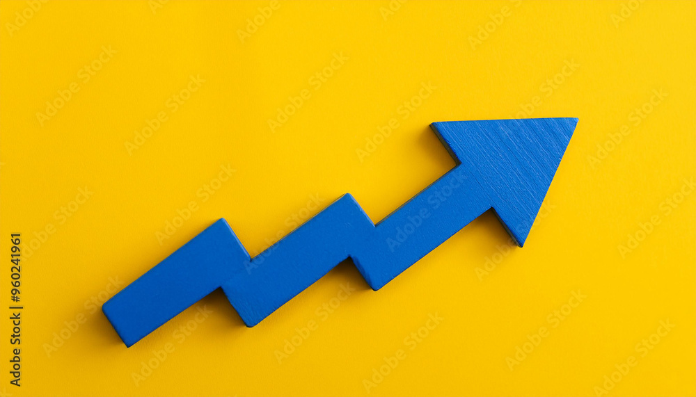 Blue wooden arrow pointing upwards on yellow background. Business and market growth. Flat lay Blue wooden arrow pointing upwards on yellow background. Business and market growth. Flat lay