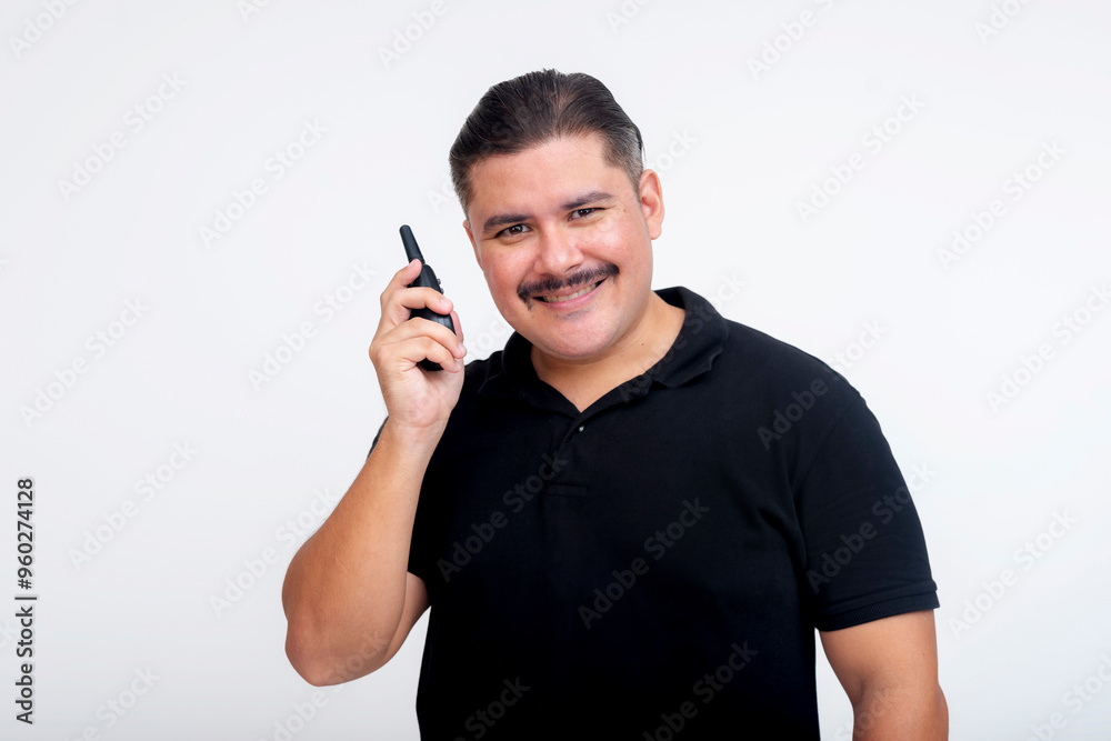 A middle-aged man in a black t-shirt smiling while talking on a two-way radio. Isolated on a white background. A middle-aged man in a black t-shirt smiling while talking on a two-way radio. Isolated on a white background.