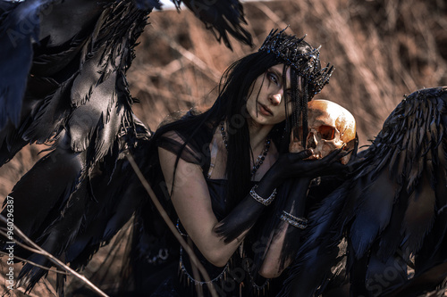 Goddess of death with black wings on a dried field