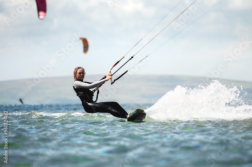 CLOSE UP, Fit Caucasian tourist kiteboarding along peninsula. Relaxed young woman surfing boarding and exploring Mediterranean coastline on sunny summer day