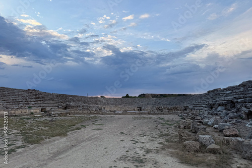 Ruins amphitheater sports arena gymnasium coliseum of ancient city in Türkiye, stone tribune architecture in beautiful nature under cloudy dramatic cinematic natural light sky